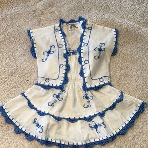 White sundress and jacket with blue trim detailing.